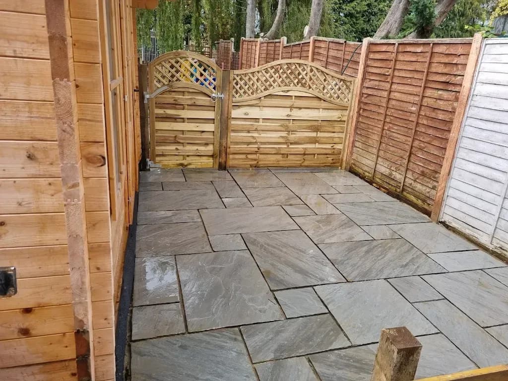 Side patio in grey sandstone with arched timber gates and fencing